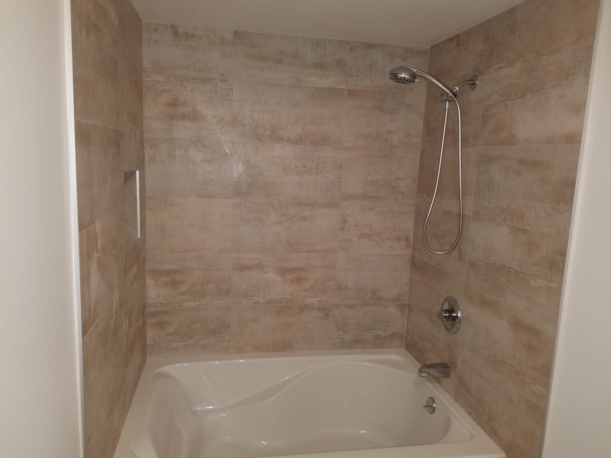 Completed bathtub surround with full-height tile and handheld shower